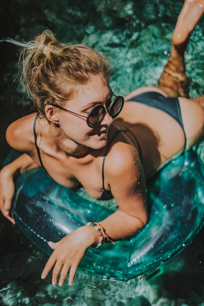 female on vacation. Beautiful young woman swims in the pool on an inflatable circle - Фото, изображение