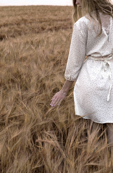 Widok kobiety przechodząca przez dojrzałe pole pszenicy - Zdjęcie, obraz