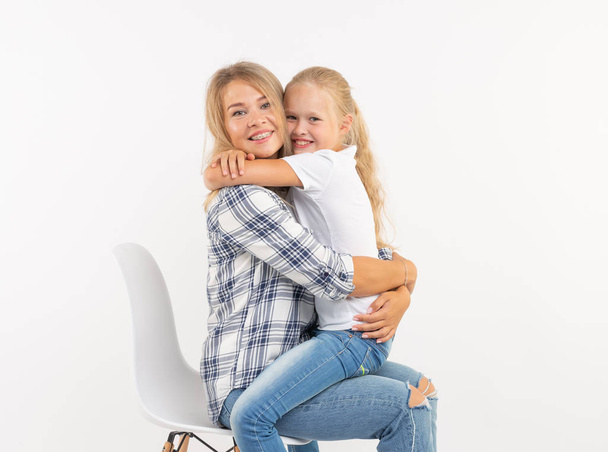 Elternschaft, Familien- und Kinderkonzept - Porträt einer Mutter und ihres Kindes, die Spaß haben und vor weißem Hintergrund lächeln - Foto, Bild