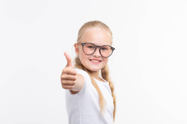 Девочка в очках, показывающих большие пальцы на белом
 - Фото, изображение