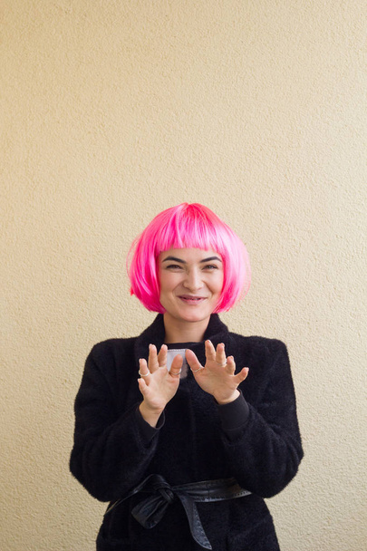 young cheerful woman in a pink wig and  black coat portrait - Foto, Imagen