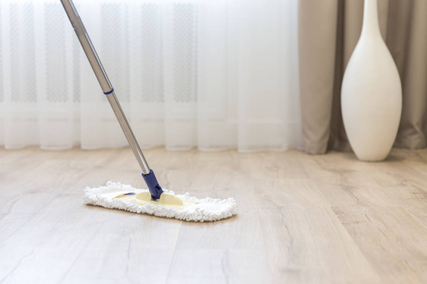 Cleaning floor with white mop near sofa - Zdjęcie, obraz