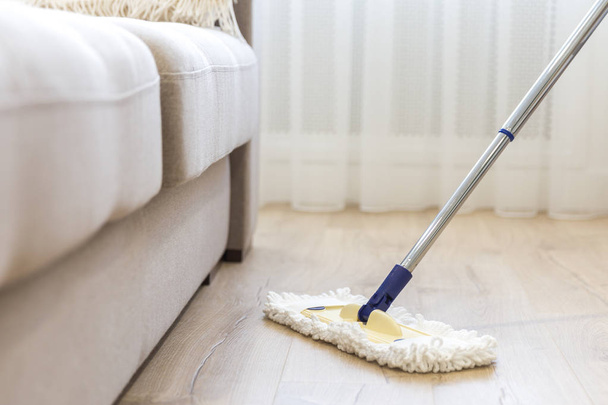 Прибирання підлоги з білим мопедом біля дивана
 - Фото, зображення