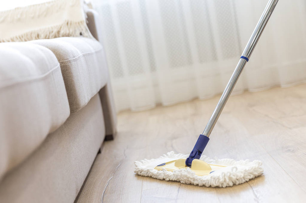 Cleaning floor with white mop near sofa - Fotografie, Obrázek