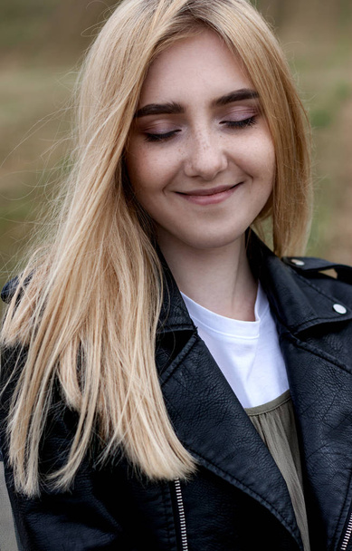 Portrait of a beautiful smiling blonde girl with freckles and closed eyes - Photo, image