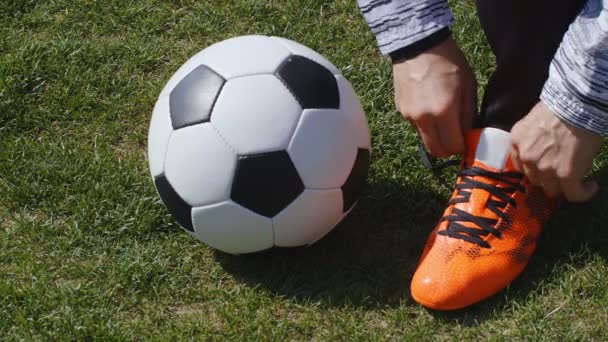 Футбол, футбольна гра. Професійний футболіст застібає червоне взуття перед тренуванням, 4k
 - Кадри, відео