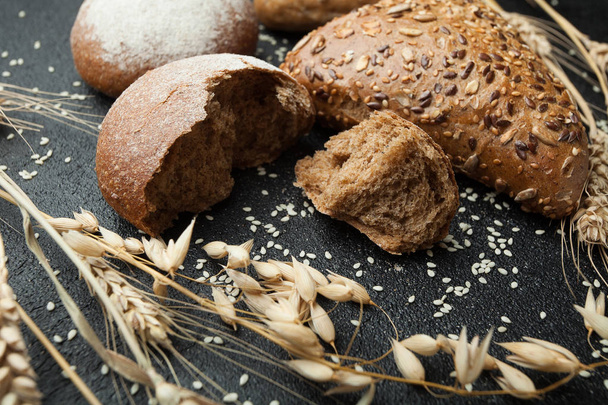 Traditional black grain bread surrounded by wheat, rye, barley o - Photo, image