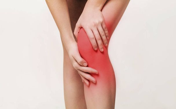 Young woman massaging her painful knee closeup - Foto, immagini
