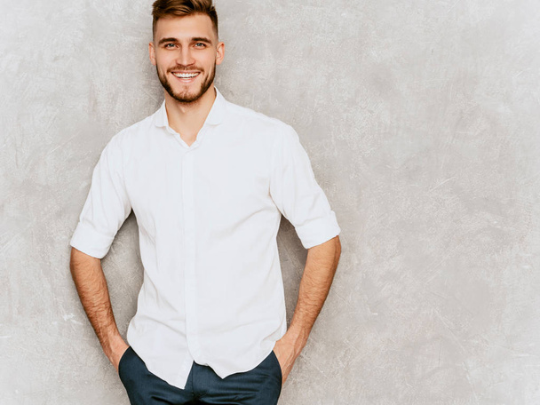 Yakışıklı gülümseyen hipster lumbersexual işadamı modeli giyiyor rahat yaz beyaz gömlek portresi. Moda şık adam gri duvara poz - Fotoğraf, Görsel