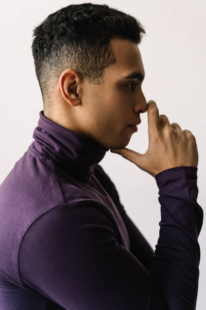 Mixed race fashion model posing for pictures in studio isolated on white background. Close up portrait of attractive African American man with emotional face  in stylish purple turtleneck - Фото, зображення