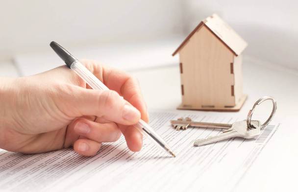 hypotheek en woninghuur. Sleutels, huis en hand die documenten ondertekenen - Foto, afbeelding