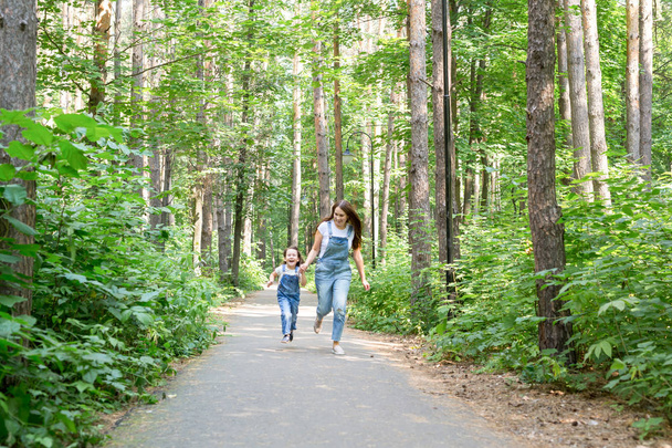 Концепція сім'ї та природи - приваблива молода жінка розважається зі своєю маленькою донькою в парку
 - Фото, зображення