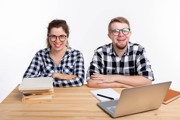 Education, students, people concept - funny couple of teens in glasses look like nerds sitting at the table - Foto, Imagen