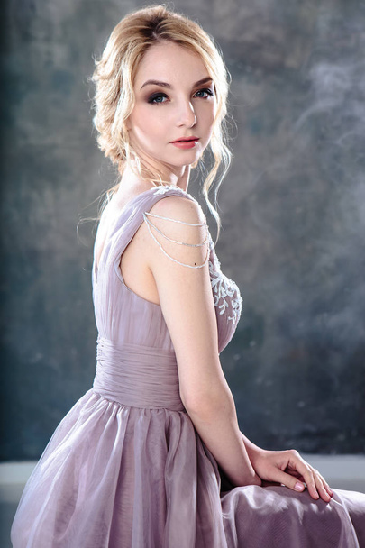 Bride blonde woman in a modern color wedding dress with elegant hair style and make up. Fashion beauty portrait over textured background - 写真・画像