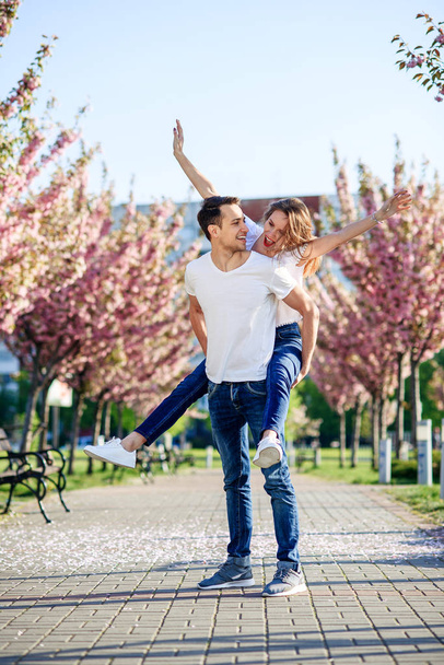 Passion and love concept. Man and woman kissing in blooming garden on spring day. Couple hugs near sakura trees. Couple in love spend time in spring garden. - Valokuva, kuva