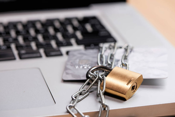 Close up of credit card and laptop with chain and padlock. - Foto, imagen