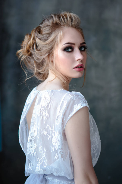 Bride blonde woman in a modern color wedding dress with elegant hair style and make up. Fashion beauty portrait over textured background - 写真・画像