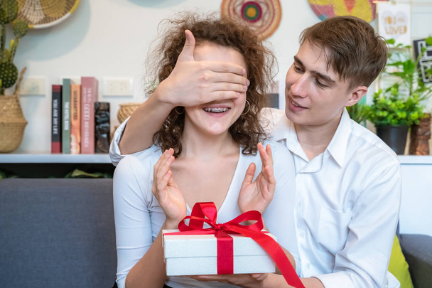 Giovane uomo che fa un regalo a una giovane donna chiudendo gli occhi
. - Foto, immagini