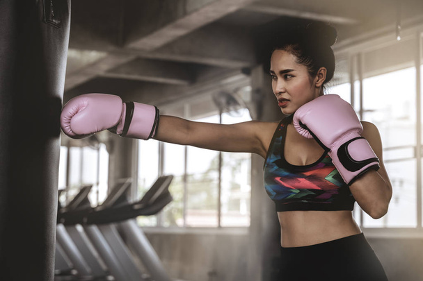 Hermosas mujeres asiáticas están perforando sacos de arena en el gimnasio, ideas de ejercicio, pérdida de peso, musculación y defensa personal
. - Foto, Imagen