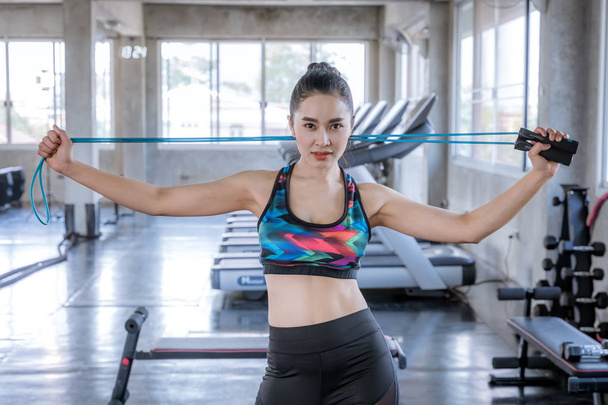 Standing woman holding a rope in the gym, a healthy exercise concept - Photo, Image