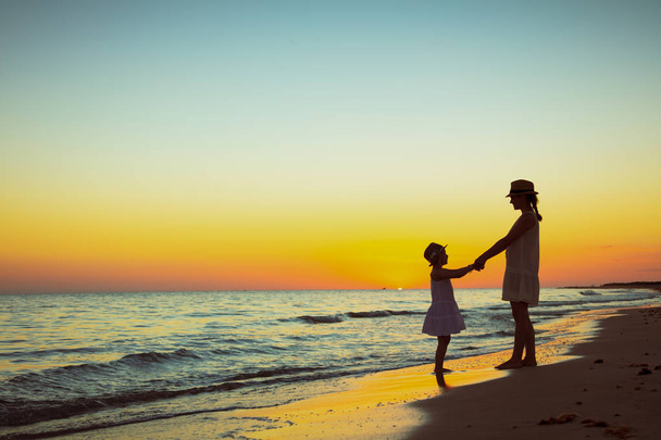 anya és lánya az óceán partján, a naplemente birtoklás móka idő - Fotó, kép