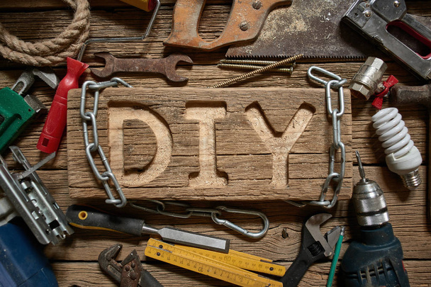 DIY letters on a wooden board on the background of working tools. Do It Yourself concept. - Photo, Image