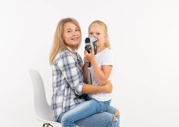Family, photography and hobby concept - woman and her child using an old fashioned camera on white background - Photo, Image