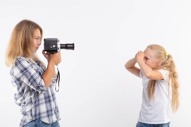 Technológiák, a fényképezés és a fő koncepció - szőke fiatal nő, retro fényképezőgép, fényképezés egy kislány felső fehér háttér - Fotó, kép