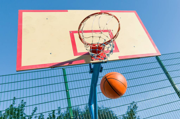Basket-ball de rue, gros plan de l'anneau de basket-ball et balle volant dans le panier
 - Photo, image