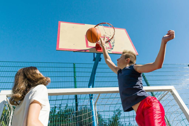 Streetball basketball game with two players, teenagers girl and boy, morning on basketball court - Zdjęcie, obraz