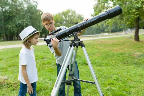 Children teenagers in the park looking through a telescope - Φωτογραφία, εικόνα