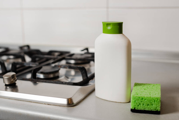 Cleaning product in plastic bottle at gas stove. - Foto, imagen