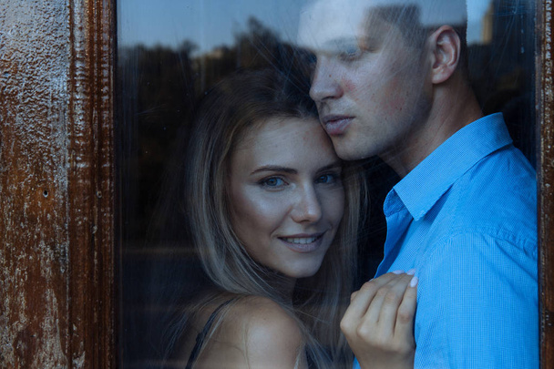 couple in love, a man hugs a girl behind the glass. - Фото, зображення