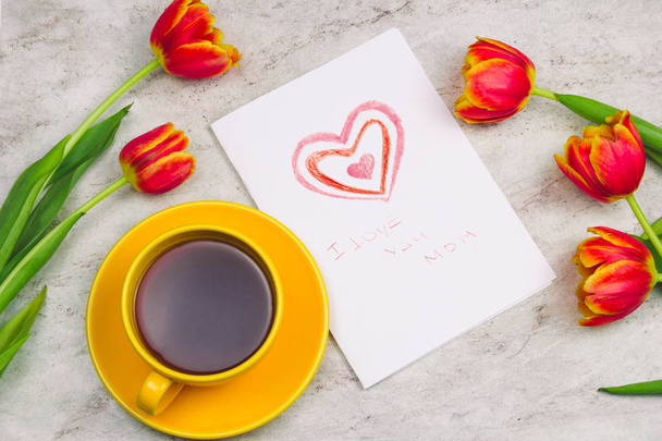 beautiful tulips ,cup of drink and handmade card with kid's drawing  for Mother's Day on marble background, top view - Фото, изображение