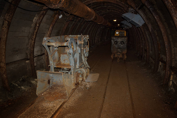 Παλιά και σκουριασμένο ορυχείο μηχανή και το τρένο με βαγόνια στο ορυχείο άξονα w - Φωτογραφία, εικόνα