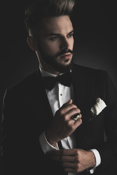man in tuxedo fixing his sleeve while looking away - Photo, Image