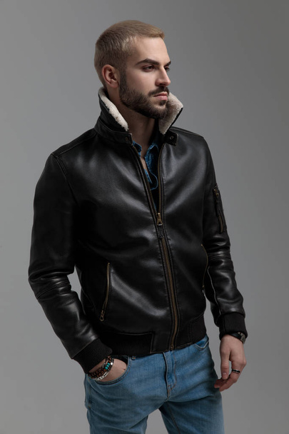blonde guy in blue jeans and leather jacket looking away - Foto, Imagen