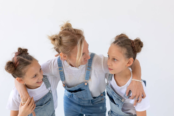 people, family and children concept - twin sisters with their mom on white background - Photo, Image