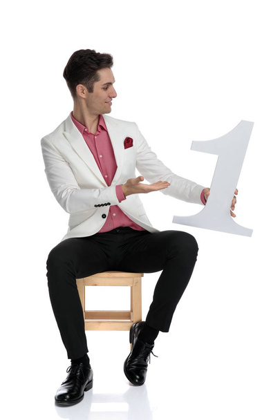 sonriente elegante hombre mostrando y señalando el brazo en el número uno
  - Foto, imagen