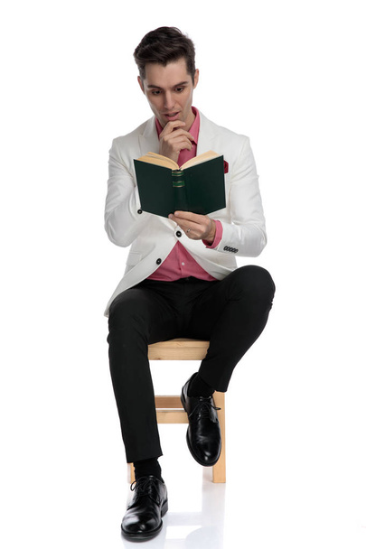 Καθιστός άνδρας που κομψό γοητεύεται από το ενδιαφέρον μυθιστόρημα  - Φωτογραφία, εικόνα