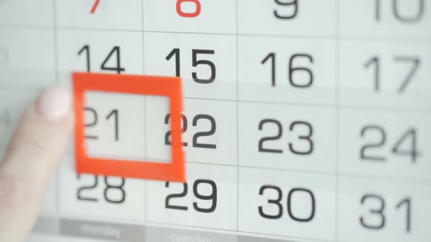 Womans hand in office changes date at wall calendar. Changes 21 to 22 - Footage, Video