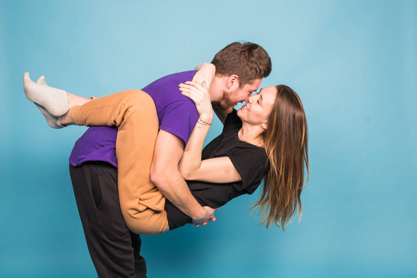 People, relationship and fun concept - Smiling man holding beautiful woman over blue background - Фото, зображення