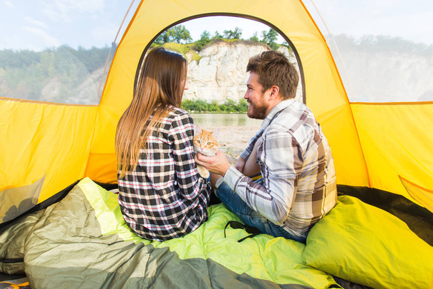 people, summer tourism and nature concept - young couple resting in camping tent, view from inside - Photo, Image