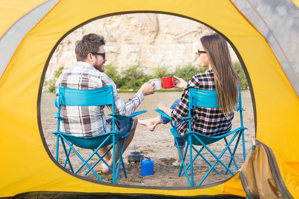People, tourism and nature concept - Cute couple sitting near yellow tent - Photo, Image