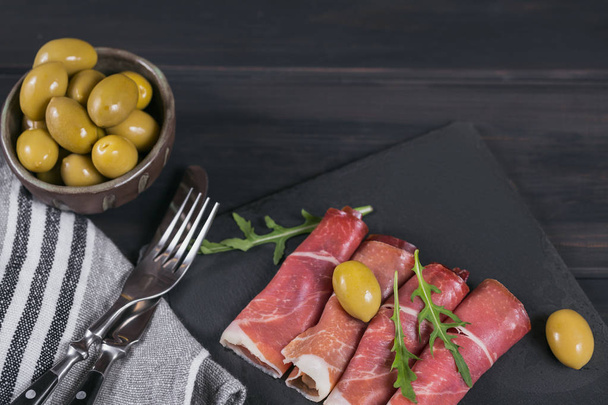 Black stone platter with slices of cured ham or Spanish jamon se - Фото, зображення