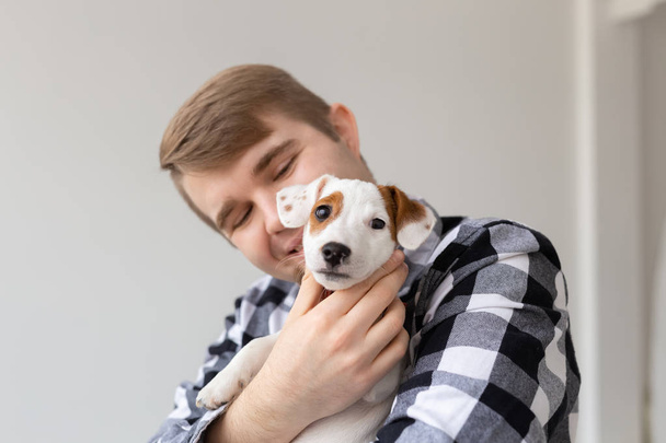 lidé, domácí zvířata a zvířata koncept - zavřít nahoru mladý muž, který držel jack russell teriér štěně - Fotografie, Obrázek