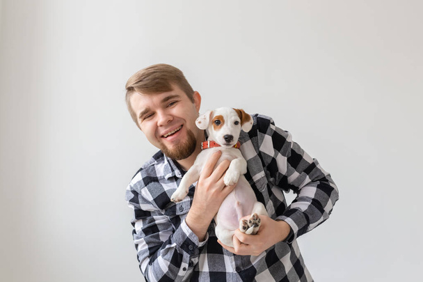 people, pets and animals concept - close up of young man holding jack russell terrier puppy on white background - Valokuva, kuva