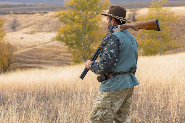 Jäger mit Hut und Gewehr auf der Suche nach Beute in der Steppe, zielt auf Beute - Foto, Bild