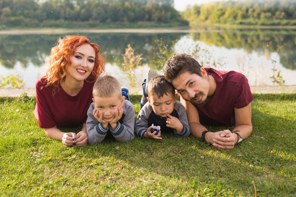 Concept de parentalité, nature, personnes - famille avec deux fils couchés près du lac
 - Photo, image