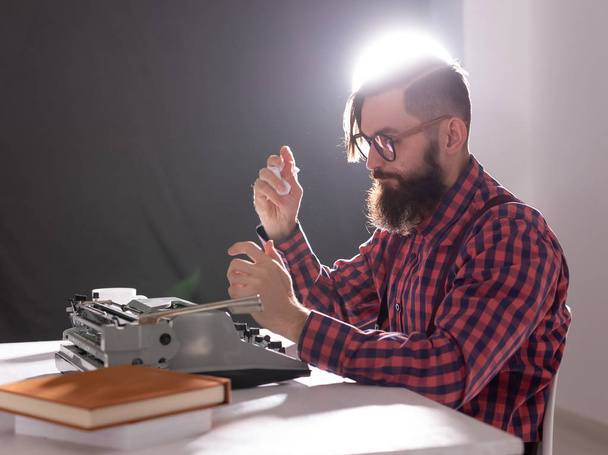 Ihmiset ja teknologian käsite - kirjailijan maailmanpäivä, komea mies, jolla on parta, joka työskentelee kirjoituskoneen kanssa mustalla taustalla
 - Valokuva, kuva